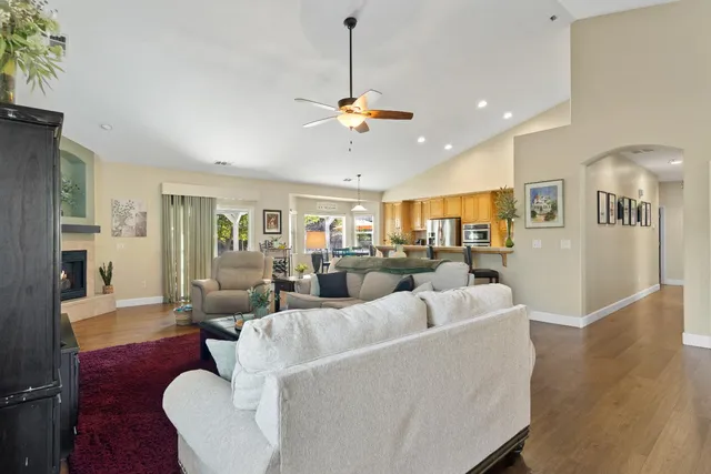 a living room with furniture kitchen view and a chandelier