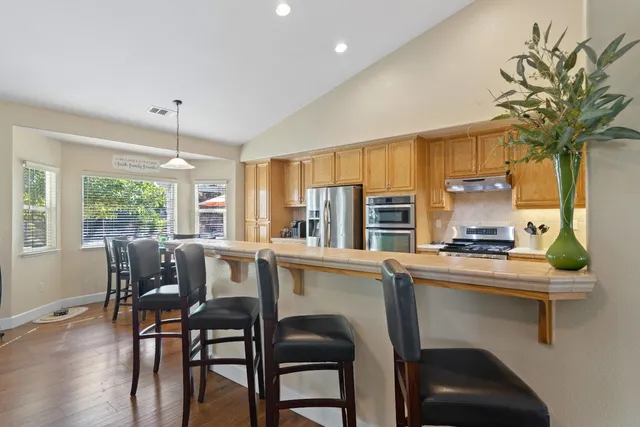 a kitchen with stainless steel appliances a table and chairs in it