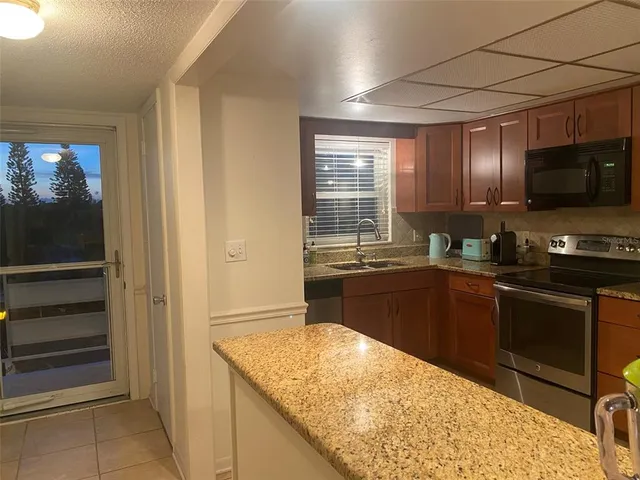 a kitchen with stainless steel appliances kitchen island granite countertop a refrigerator and a sink