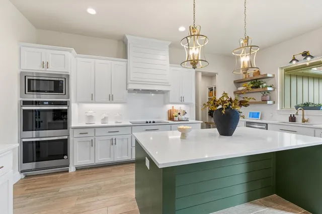 a kitchen with stainless steel appliances granite countertop a sink dishwasher a stove and a dining table with wooden floor