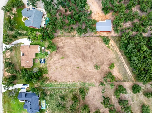 an aerial view of a house with outdoor space and trees all around