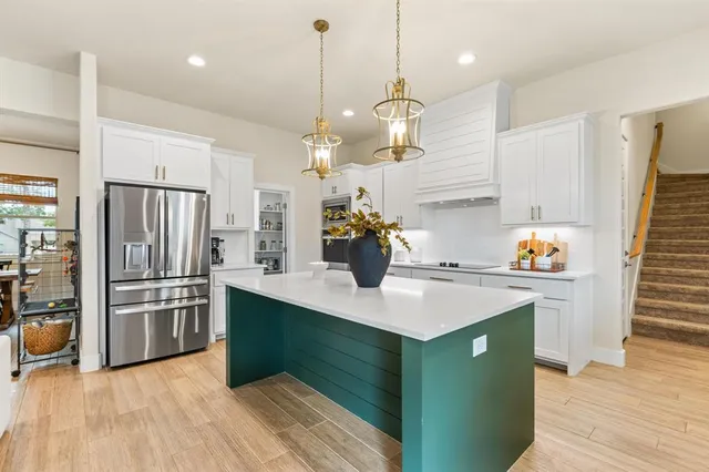 a kitchen with kitchen island white cabinets and stainless steel appliances