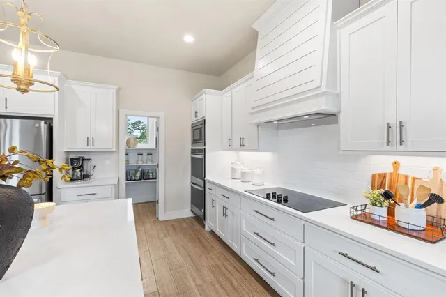 a kitchen with stainless steel appliances granite countertop a sink dishwasher stove and white cabinets with wooden floor