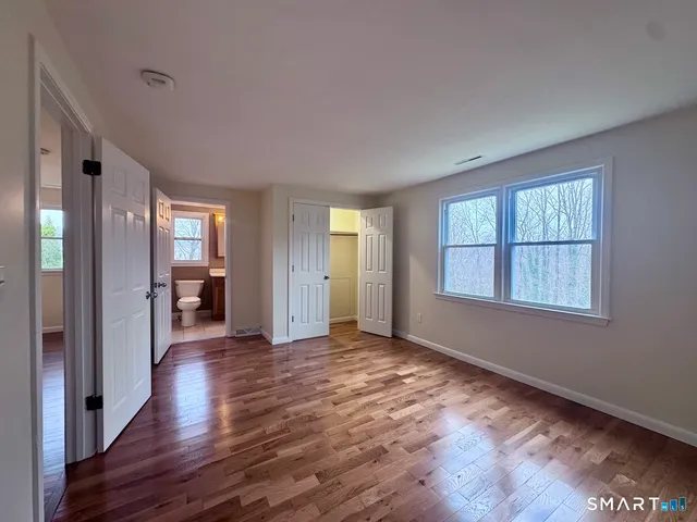 a view of an empty room with window and wooden floor
