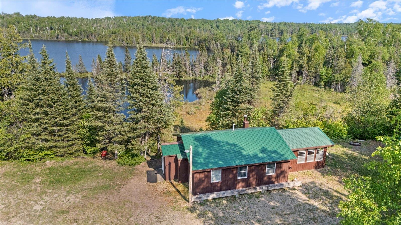 Aerial view of property and surrounding area featuring a heavily wooded area and a large body of water