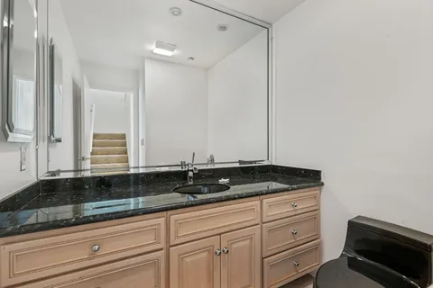 a bathroom with a granite countertop sink and white cabinets