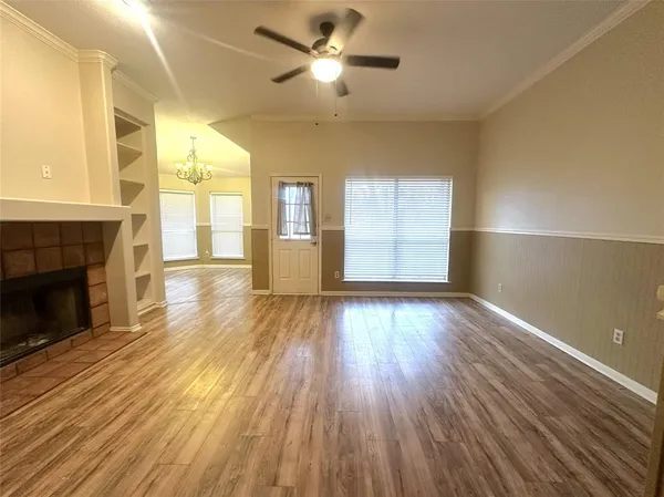 an empty room with wooden floor fireplace and windows
