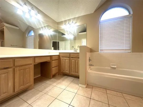 a spacious bathroom with a sink a vanity a mirror and bathtub