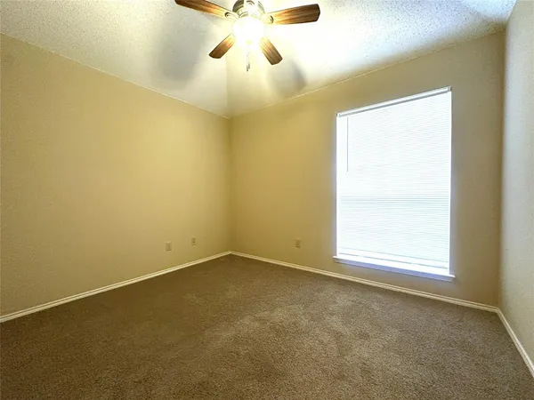 an empty room with a window and a chandelier fan