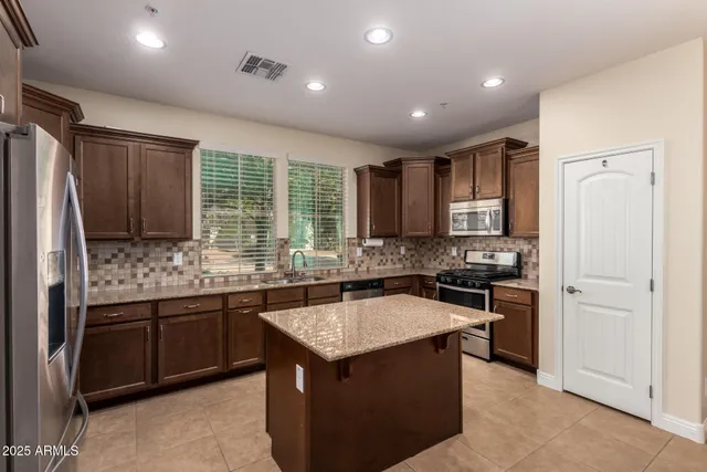 a large kitchen with stainless steel appliances granite countertop granite counter tops refrigerator a stove top oven and a sink