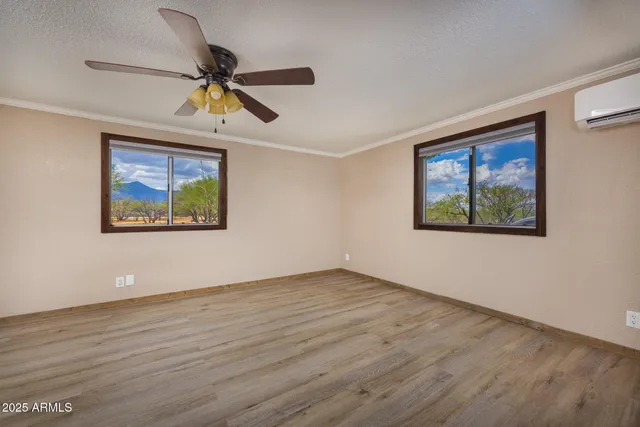an empty room with wooden floor ceiling fan and windows
