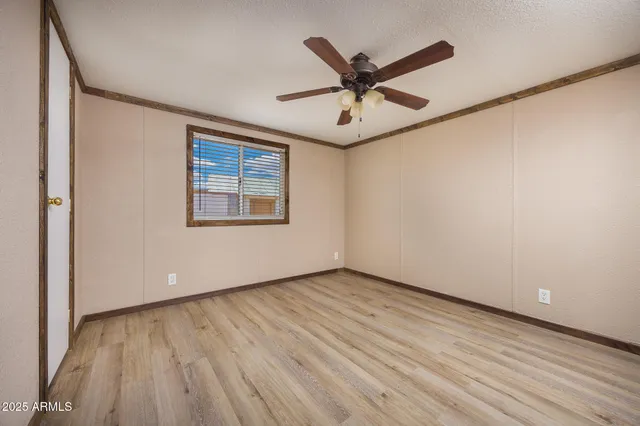 an empty room with wooden floor fan and windows