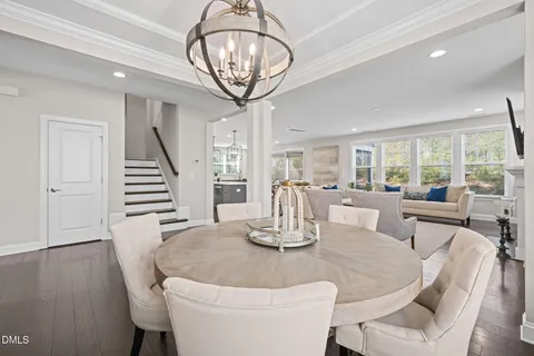 a dining room with wooden floor a chandelier a glass table and chairs
