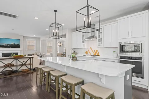 a kitchen with stainless steel appliances a dining table chairs stove and white cabinets