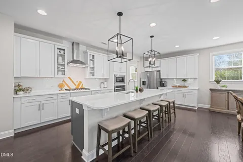 a kitchen with cabinets a sink dishwasher a island and chairs in it