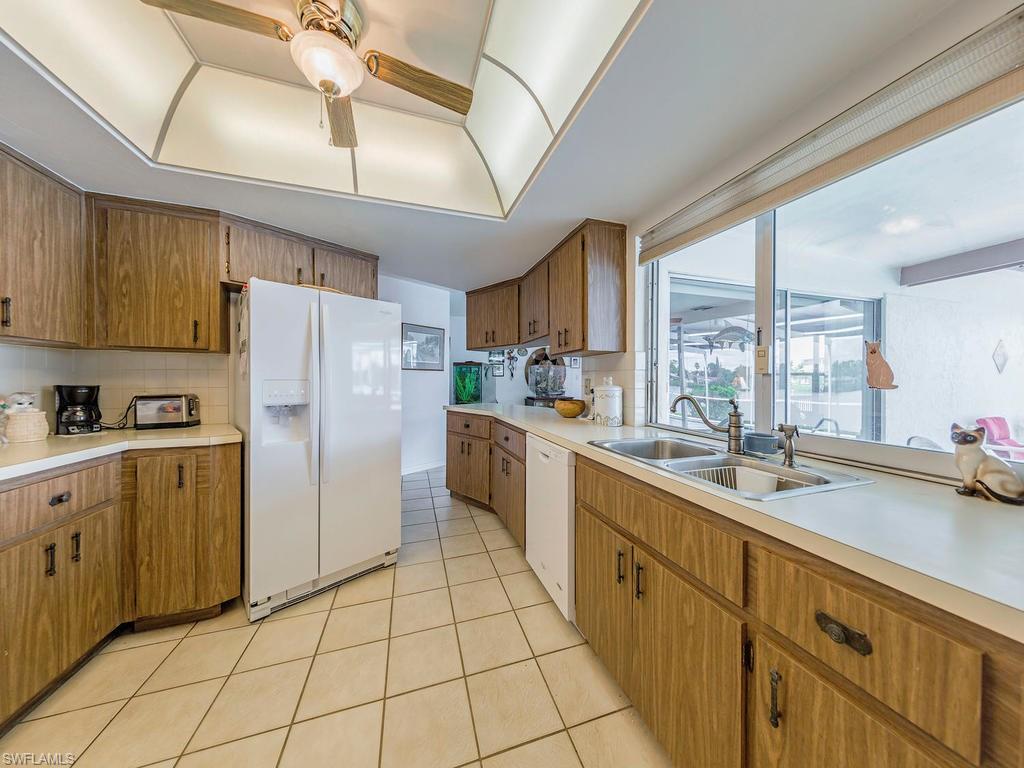 3065 50th Lane Southwest Naples, FL 34116 - Photo 12 of 25 a kitchen with a sink a refrigerator and cabinets