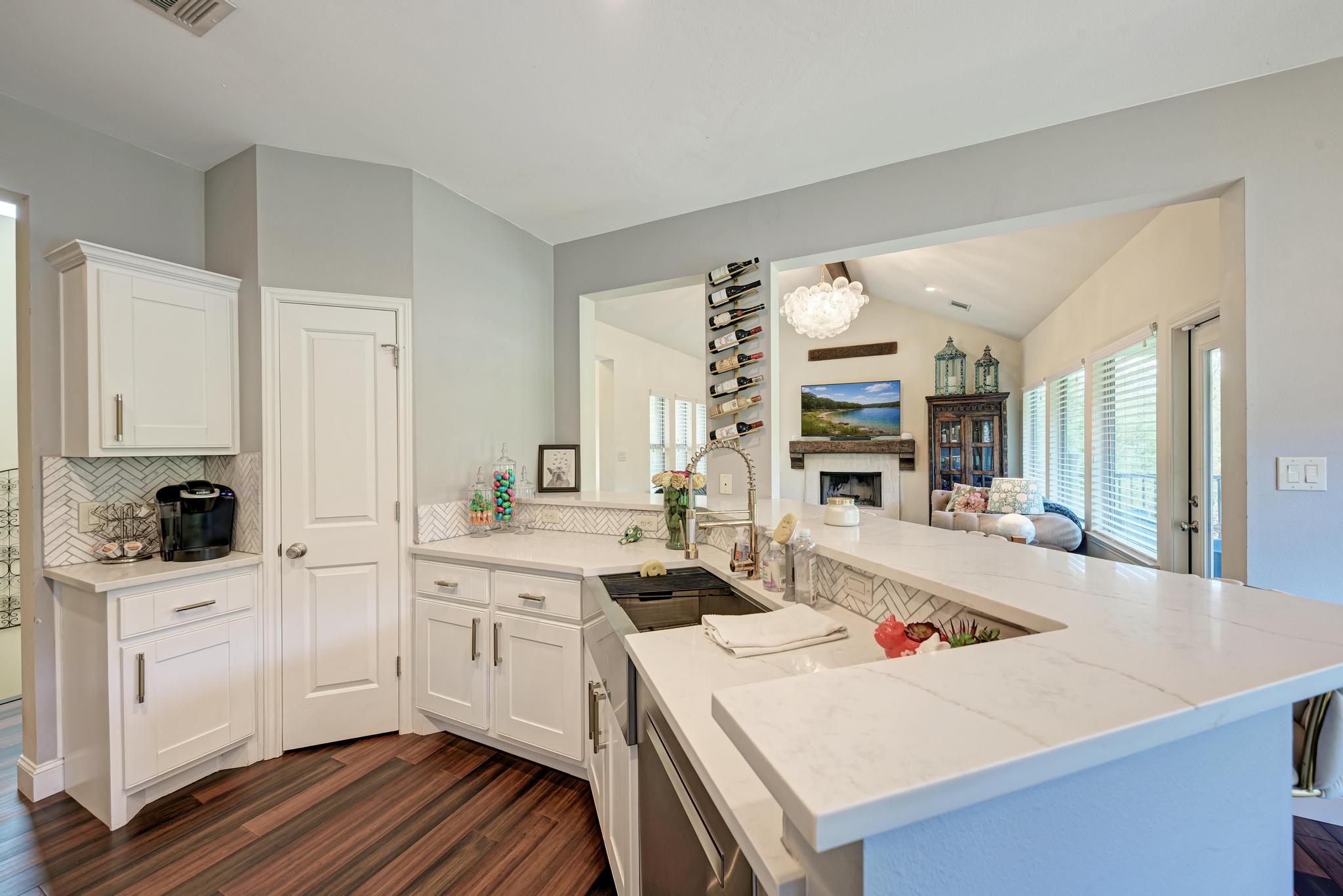 2605 Indian Creek Road Austin, TX 78734 - Photo 7 of 33 White shaker cabinetry with brushed nickel hardware, white quartz countertops, herringbone tile backsplash, and wood-finish flooring