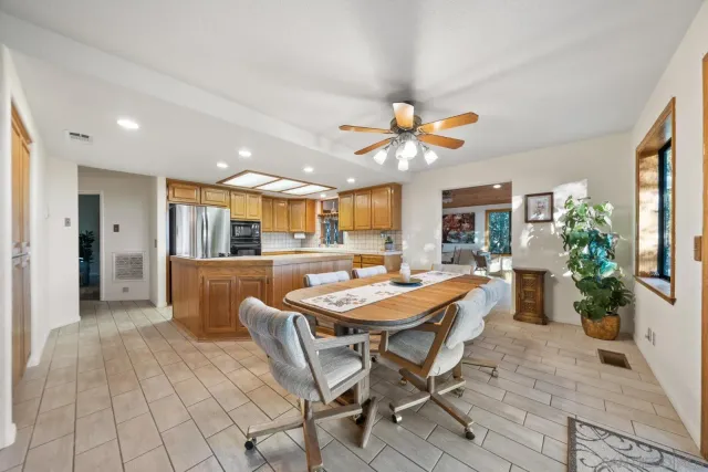 a dining hall with stainless steel appliances kitchen island granite countertop a table and chairs in it