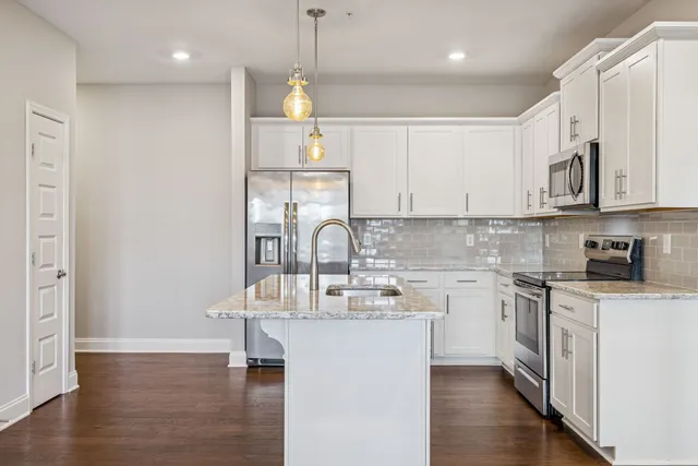a kitchen with kitchen island granite countertop a sink cabinets and wooden floor