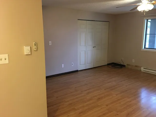 a view of an empty room with wooden floor and a window
