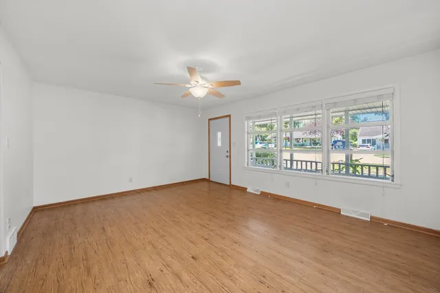 a view of an empty room with a window and wooden floor