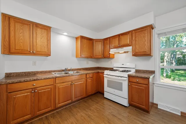 a kitchen with stainless steel appliances granite countertop wooden cabinets a sink and dishwasher with wooden floor