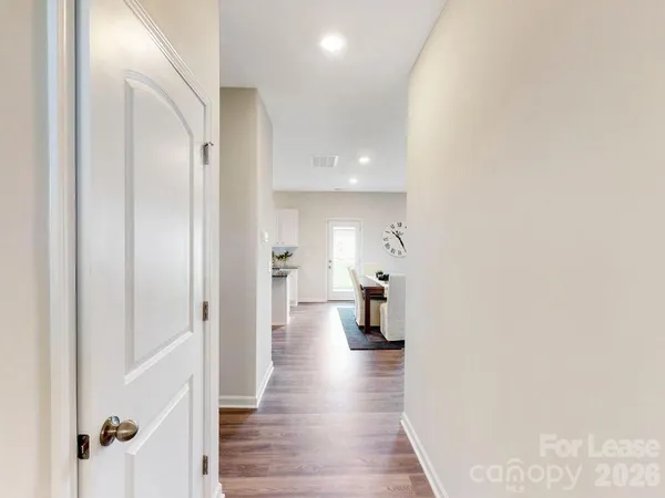 a view of a hallway with wooden floor and a bathroom