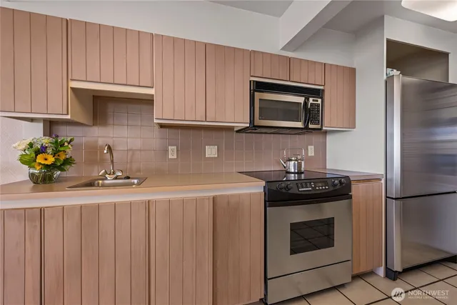 a kitchen with granite countertop stainless steel appliances wooden cabinets and a stove top oven