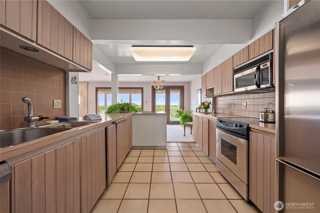 a white kitchen with stainless steel appliances granite countertop a stove a sink dishwasher and a refrigerator