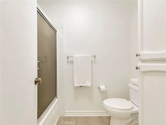 a view of an empty room with wooden floor and closet