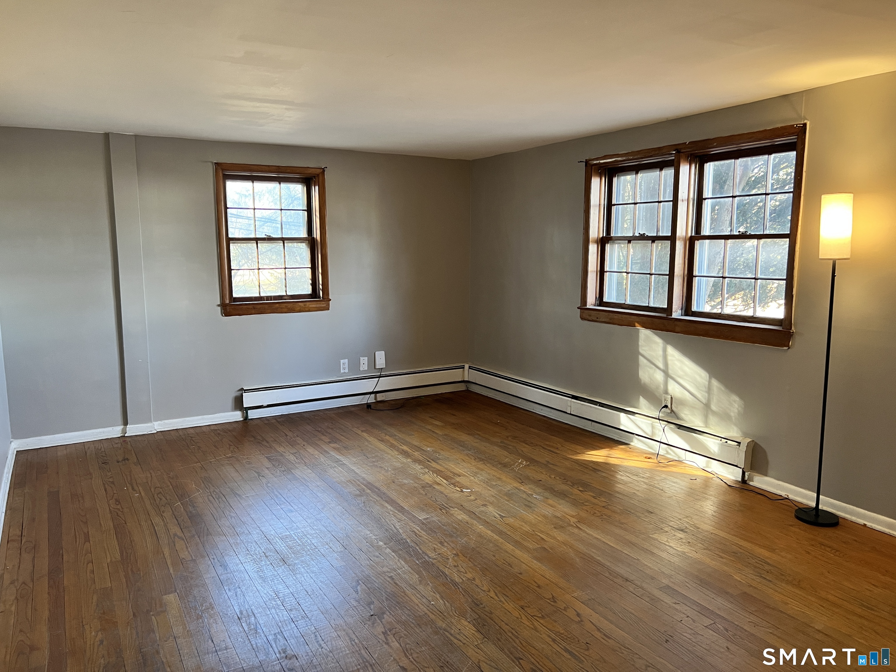 an empty room with wooden floor and windows