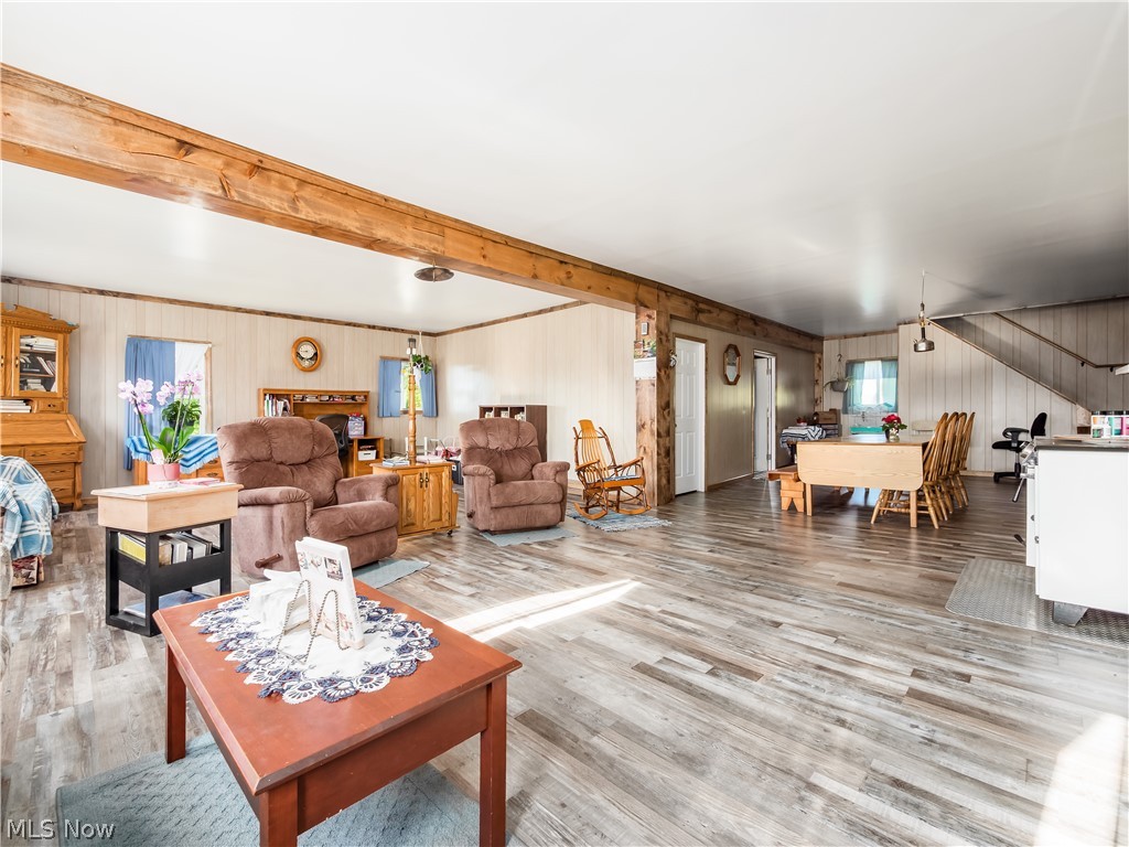4182 Tooms Road Cumberland, OH 43732 - Photo 13 of 37 Spacious interior featuring wood-finish flooring, exposed wood beams, vertical paneled walls, and a built-in staircase