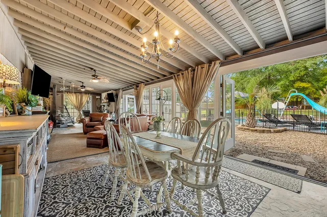 a view of a patio with table and chairs and a barbeque grill with couches and wooden roof