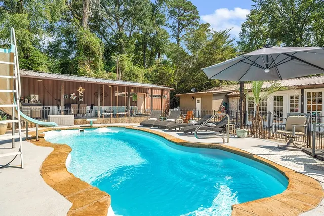 a view of swimming pool with chairs and umbrella