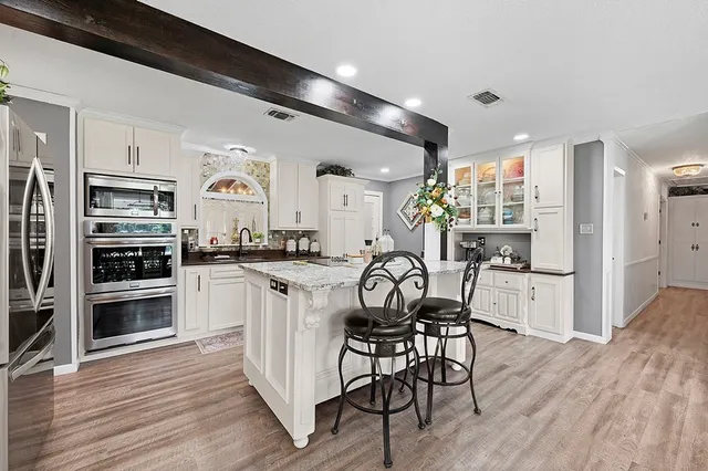 a kitchen with stainless steel appliances a dining table chairs stove and refrigerator