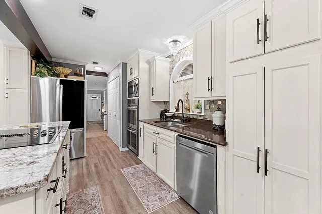 a kitchen with stainless steel appliances granite countertop a lot of counter space and wooden floors