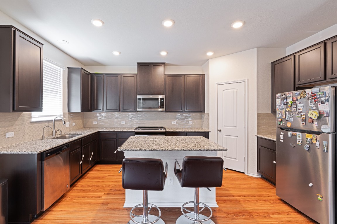 2950 East Old Settlers Boulevard, Unit 3 Round Rock, TX 78665 - Photo 2 of 28 a large kitchen with kitchen island granite countertop wooden cabinets and a refrigerator