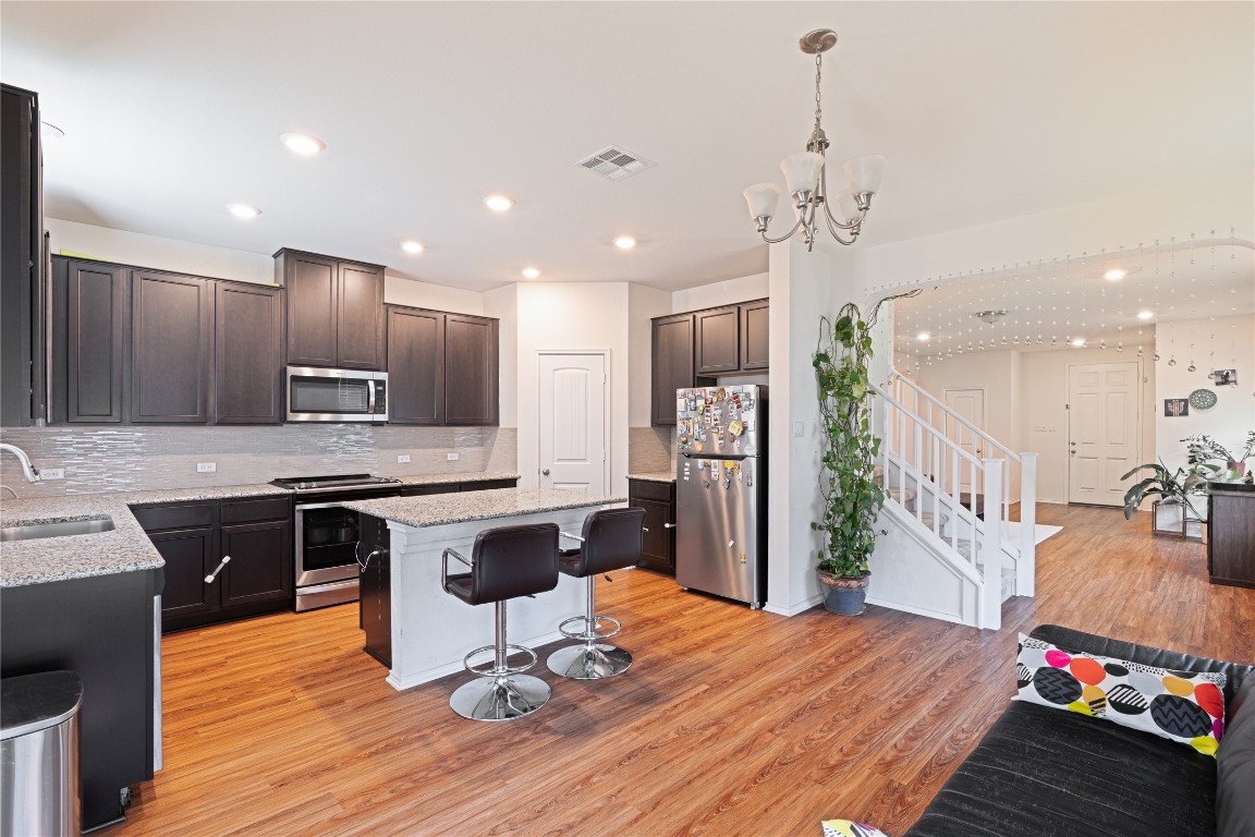 2950 East Old Settlers Boulevard, Unit 3 Round Rock, TX 78665 - Photo 6 of 28 a open kitchen with stainless steel appliances granite countertop a refrigerator dining table and chairs with wooden floors