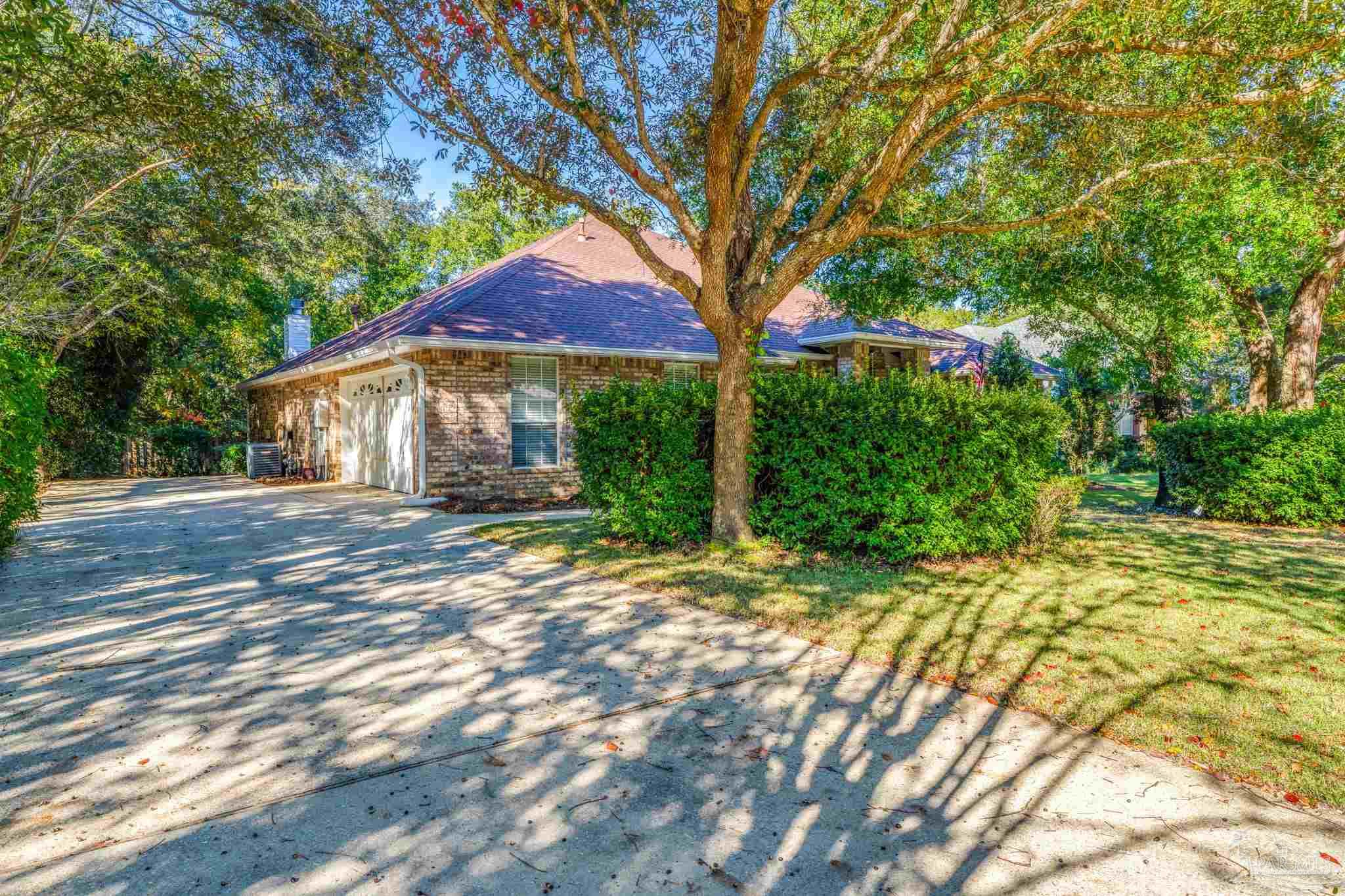 10149 Bittern Drive Pensacola, FL 32507 - Photo 44 of 56 a backyard of a house with large trees and outdoor seating