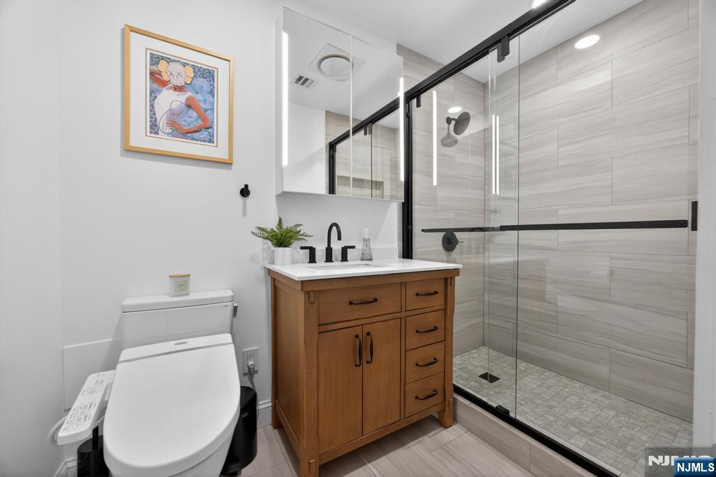 653 Ridgewood Avenue Bloomfield, NJ 07003 - Photo 12 of 27 a bathroom with a toilet a sink and glass door