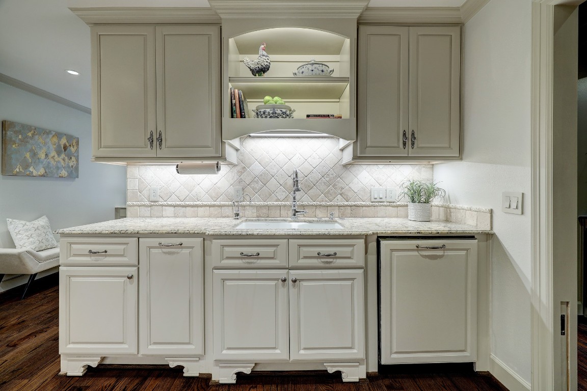 6599 Bayou Glen Road Houston, TX 77057 - Photo 22 of 41 On this wall is the deep sink with hot water dispenser, pull out spray faucet, custom paneled kitchen Aid dishwasher and custom pull out trash drawer. Charming lighted open shelving for decorative accents.