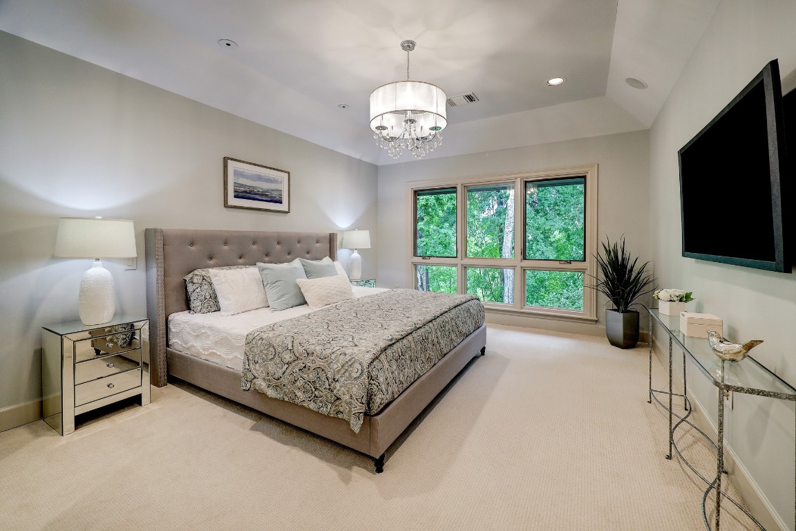 6599 Bayou Glen Road Houston, TX 77057 - Photo 26 of 41 Retreat to the spacious primary bedroom with room for a sitting area. Large 10' picture window with incredible views. The room features new carpeting, coffered ceiling with recessed lighting and two recessed accent reading lights and decorative chandelier.