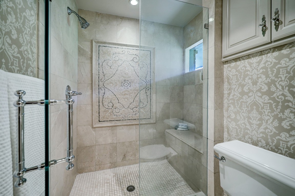 6599 Bayou Glen Road Houston, TX 77057 - Photo 29 of 41 yond the vanity area is this gorgeous walk-in shower with decorative inlay tile work, shower seat and seamless shower door.