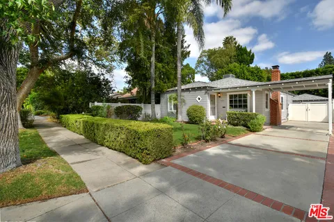 a front view of a house with a yard and potted plants