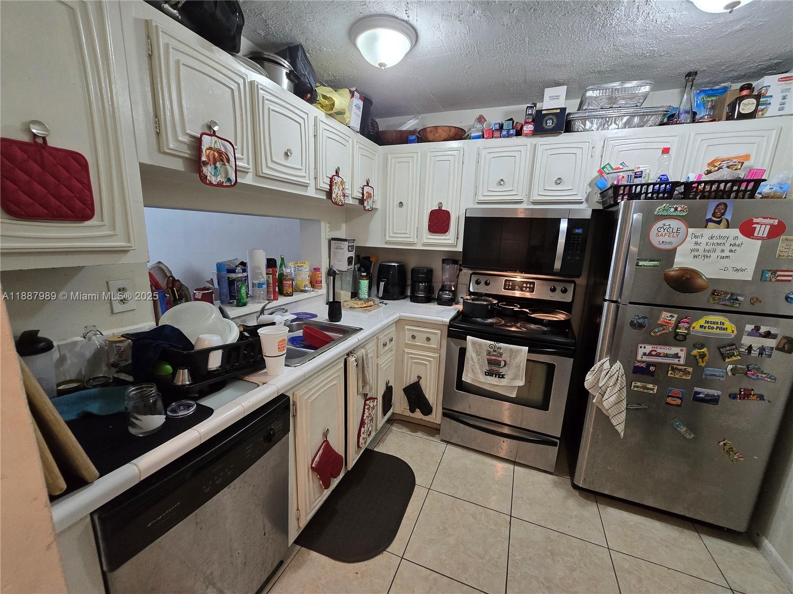 498 Northwest 165th Street, Unit D405 Miami, FL 33169 - Photo 3 of 12 a kitchen with a white stove top oven and cabinets