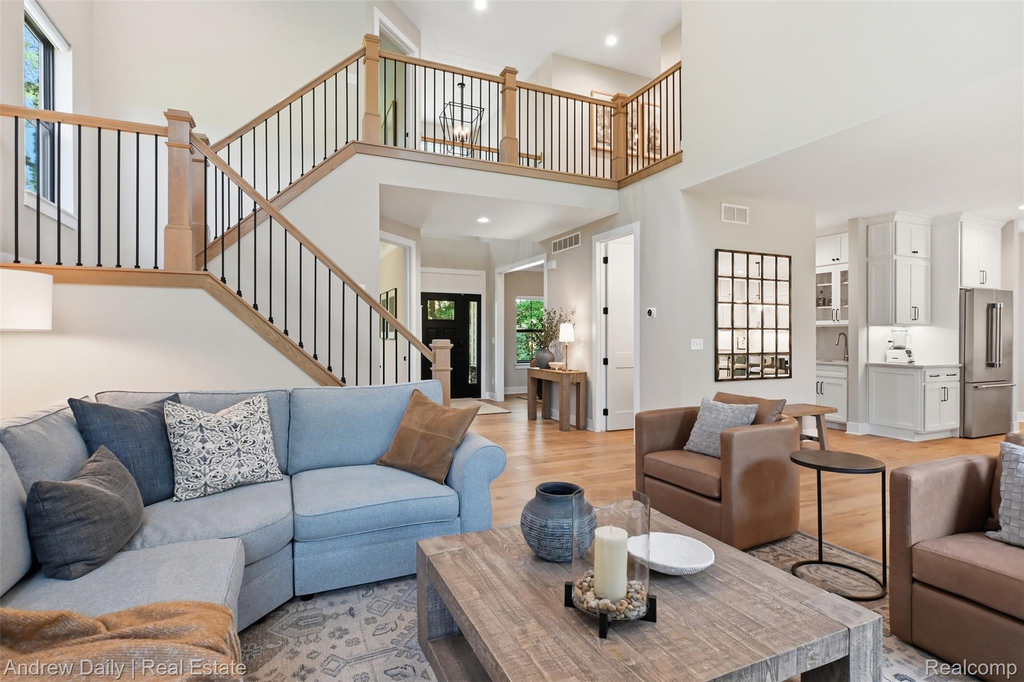 4661 Spears Road Pinckney, MI 48169 - Photo 15 of 56 Open-concept living space featuring wood-finish flooring, a two-story ceiling, and a prominent staircase with natural wood railings and black metal spindles
