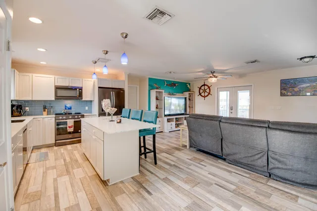 a large white kitchen with wooden floor and stainless steel appliances