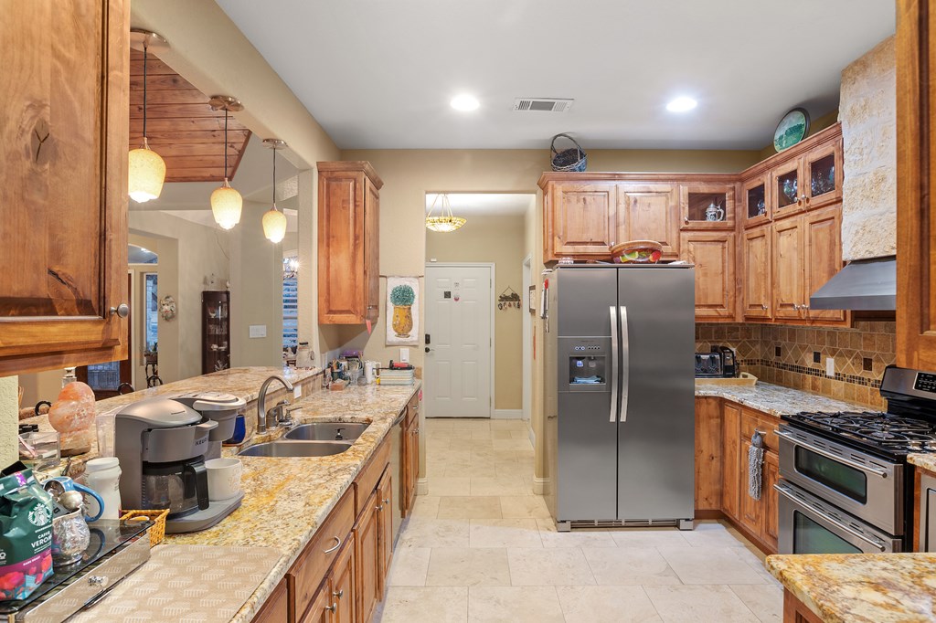 2142 Lightstone Fredericksburg, TX 78624 - Photo 20 of 30 a kitchen with stainless steel appliances granite countertop a refrigerator a stove and a sink with wooden floor