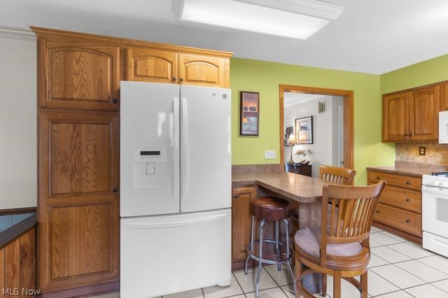 815 North Road Niles, OH 44446 - Photo 14 of 27 Kitchen with a breakfast bar, white appliances, and light tile patterned floors