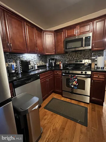 a kitchen with stainless steel appliances granite countertop wooden cabinets a stove top oven a sink and dishwasher